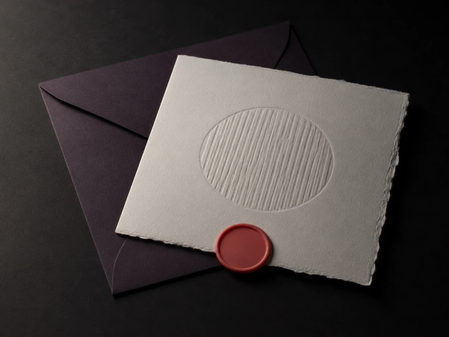 A square deckle-edged invitation card in thick bone cotton stock on its envelope, with a coral wax seal and a deep blind emboss