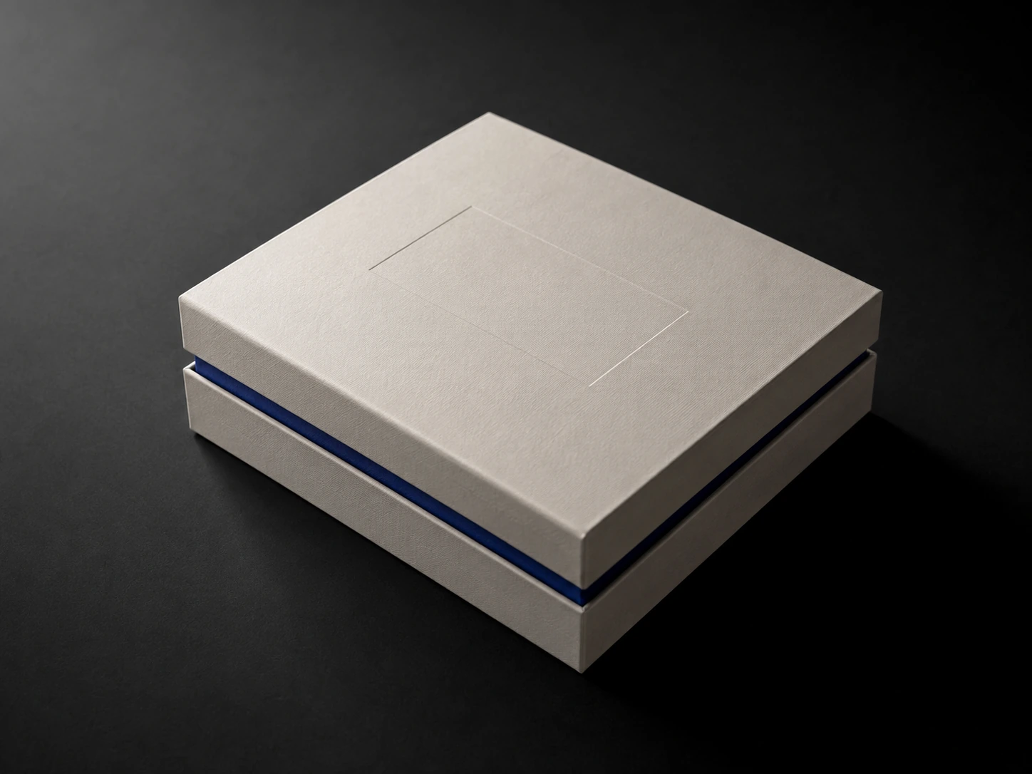 Closed two-piece rigid gift box in bone board, lid slightly offset to show a cobalt-lined interior edge