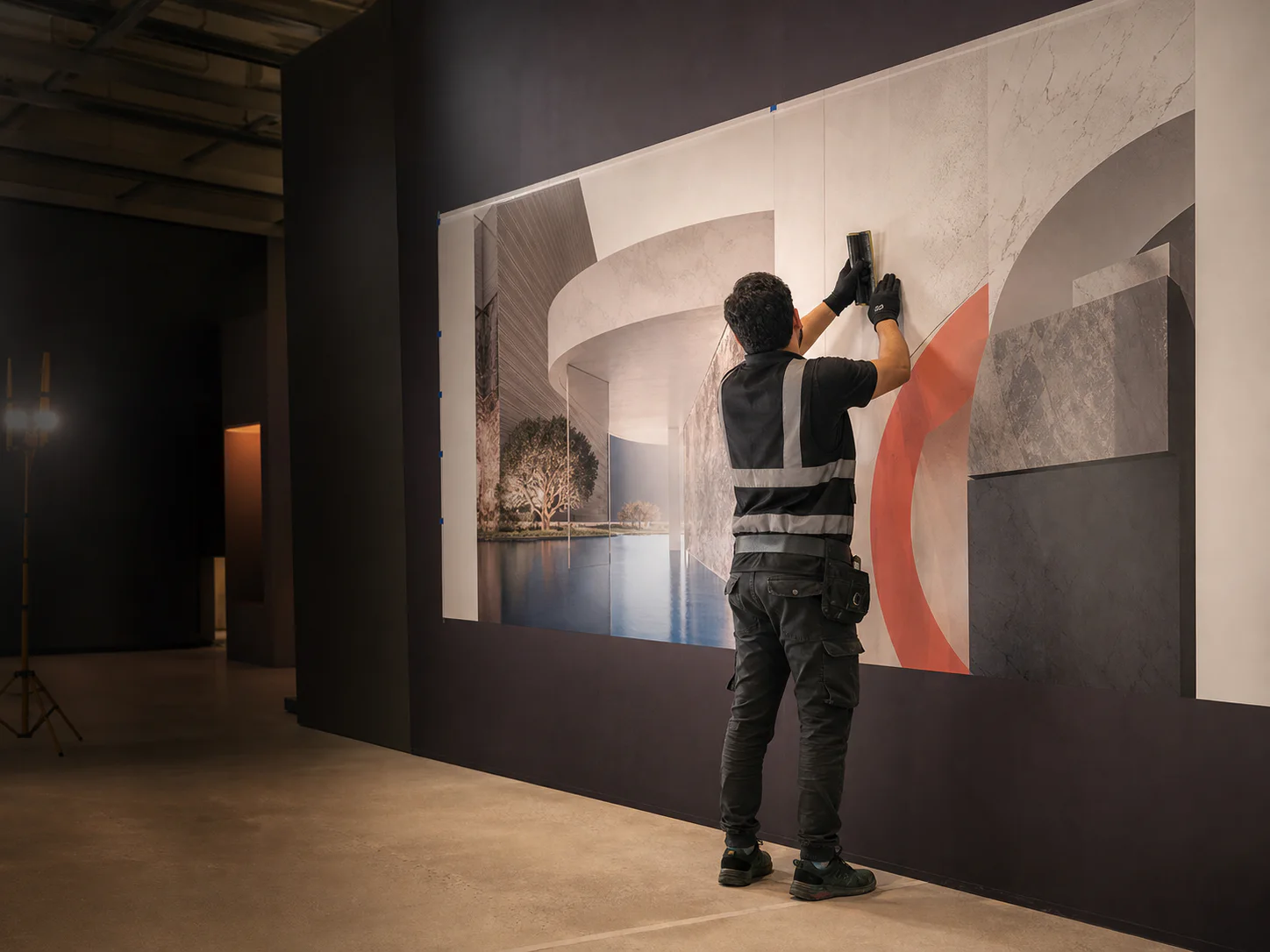 Professional installer aligning a large printed architectural graphic inside an exhibition space
