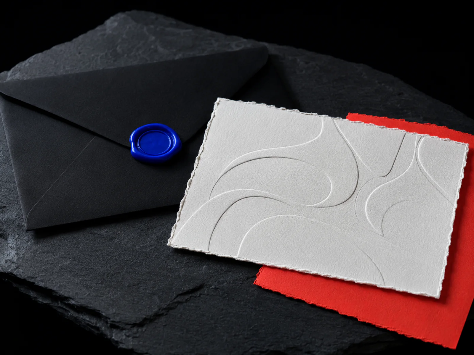 Deckle-edge embossed invitation with a cobalt wax seal and a coral card